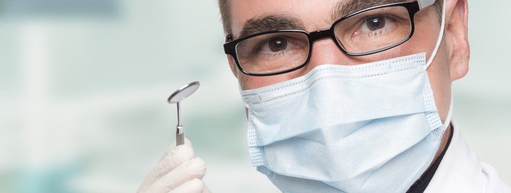 A dentist with a mask on and holding a dental tool