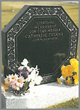 Octagonal shaped Black granite memorial with polished rose design in relief, sitting on a splayed corner base with two flower containers.