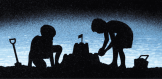 Two children are building a sand castle on the beach at night.