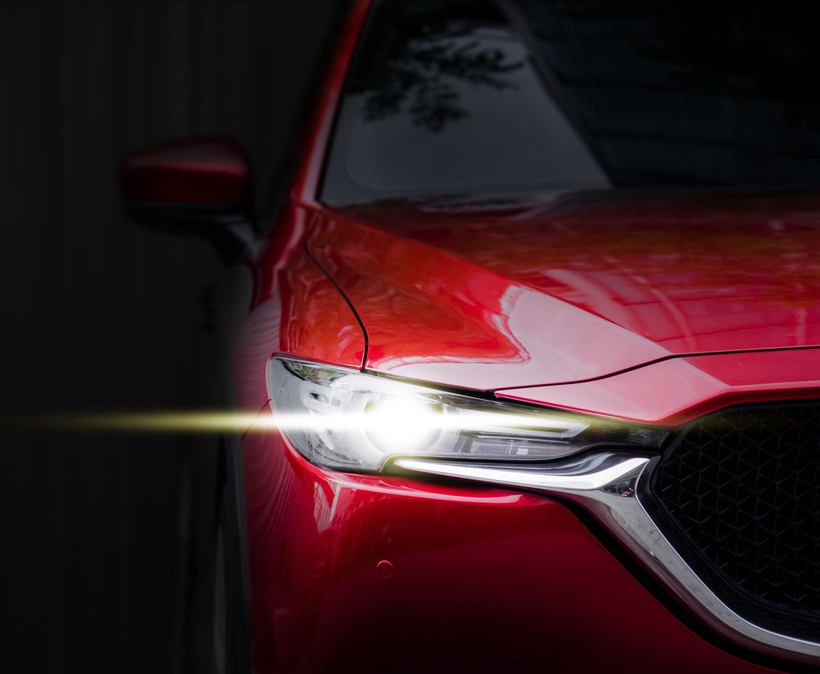 A Close Up of a Red Car With the Headlights on