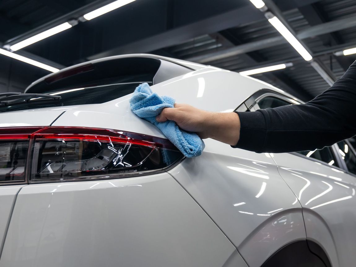 A Person is Cleaning a White Car With a Blue Cloth