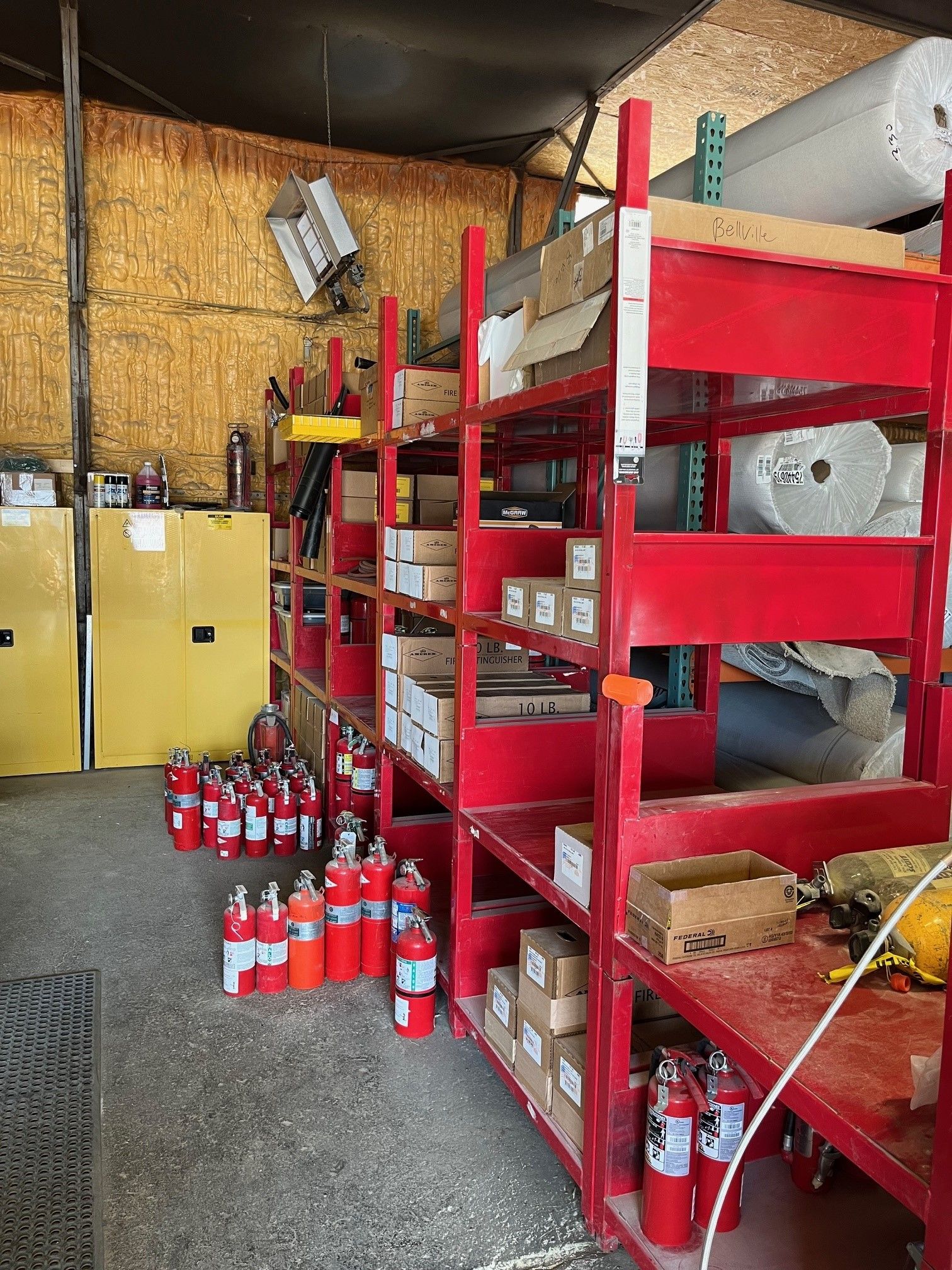 A warehouse filled with lots of red shelves and fire extinguishers.