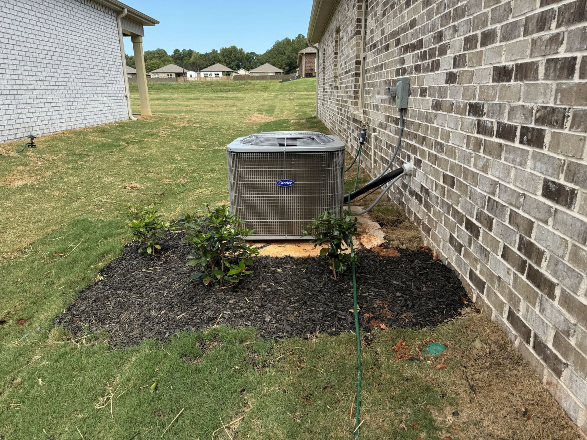 An air conditioner is sitting on the side of a brick building.