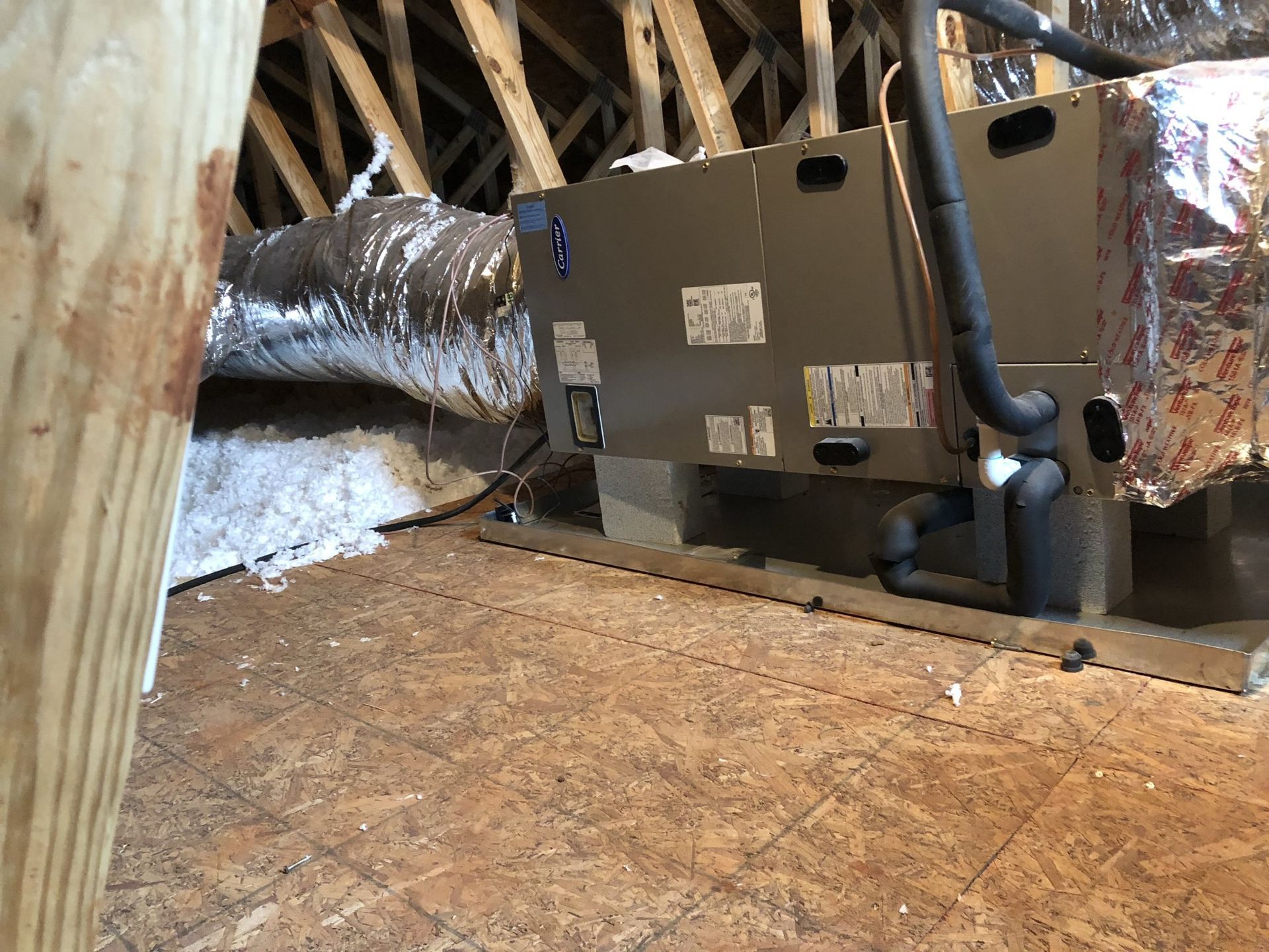 An air conditioner is sitting in the attic of a house.