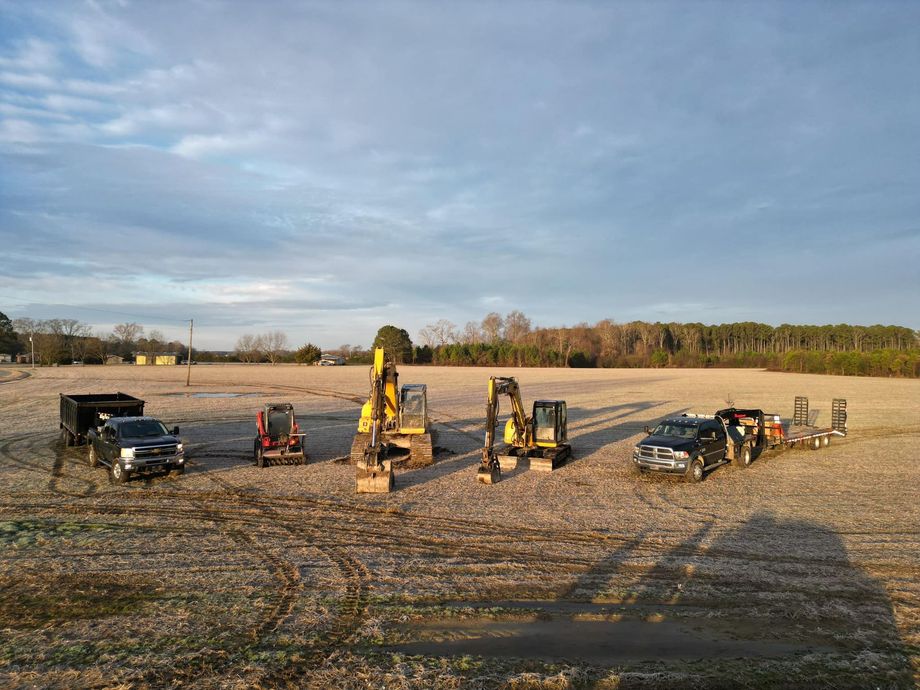 A group of construction vehicles are parked in a field.