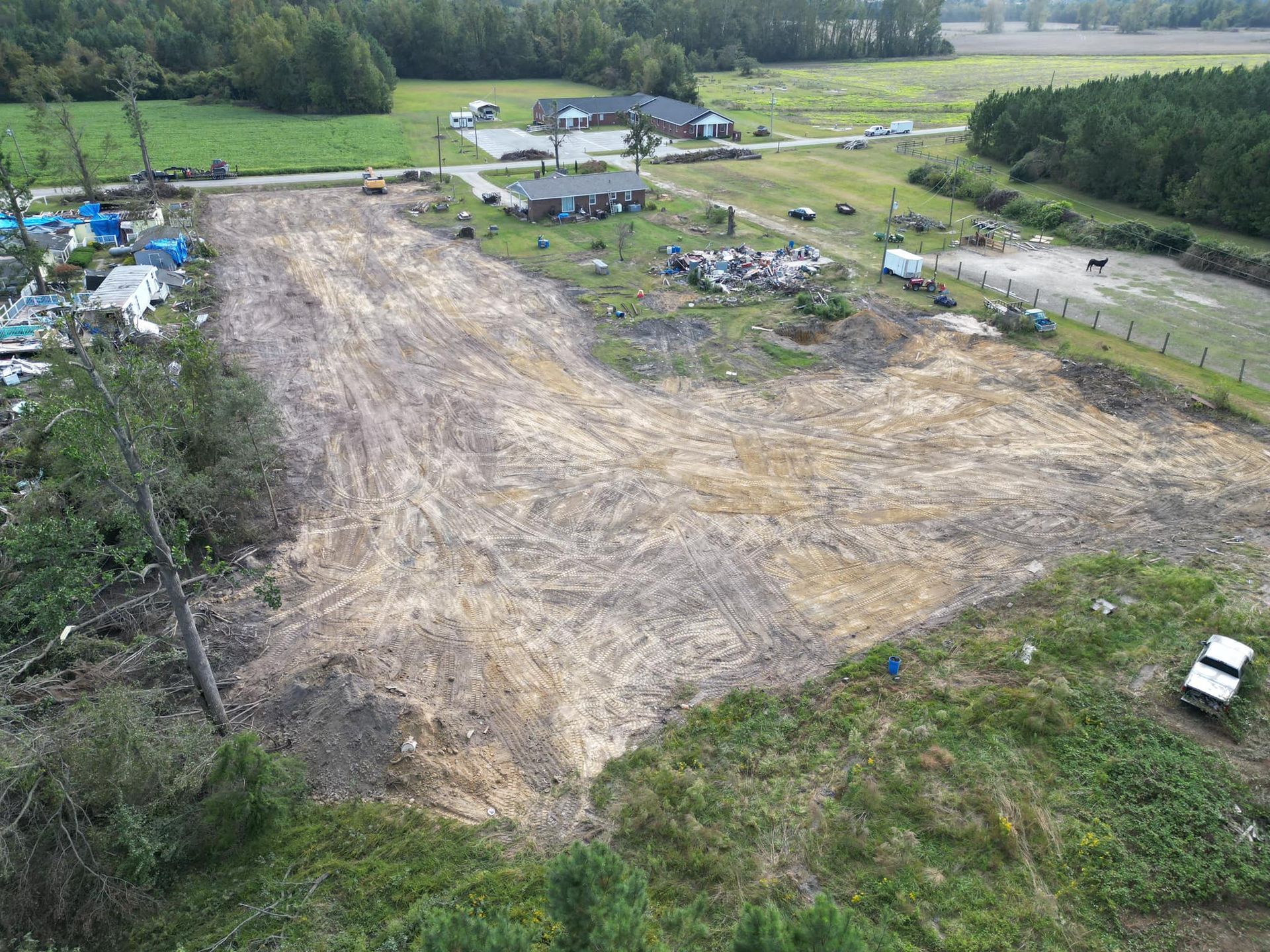 An aerial view of a large dirt field with a house in the background.