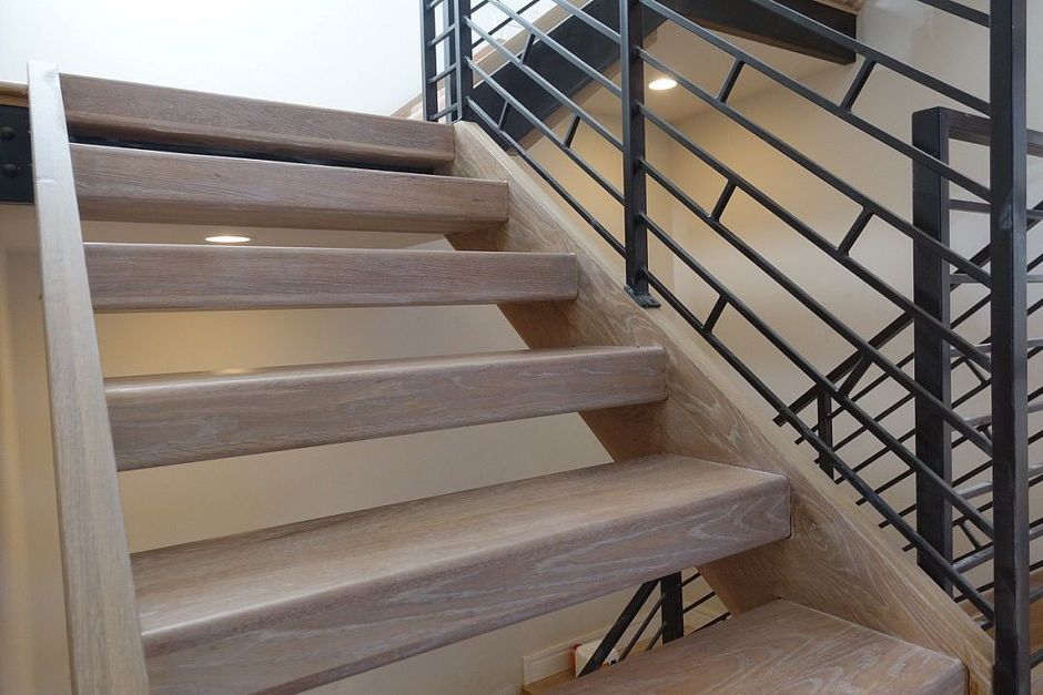 a wooden stair case next to a metal handrail