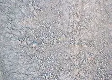 Close-up of a light gray, speckled stone or concrete surface with a rough texture