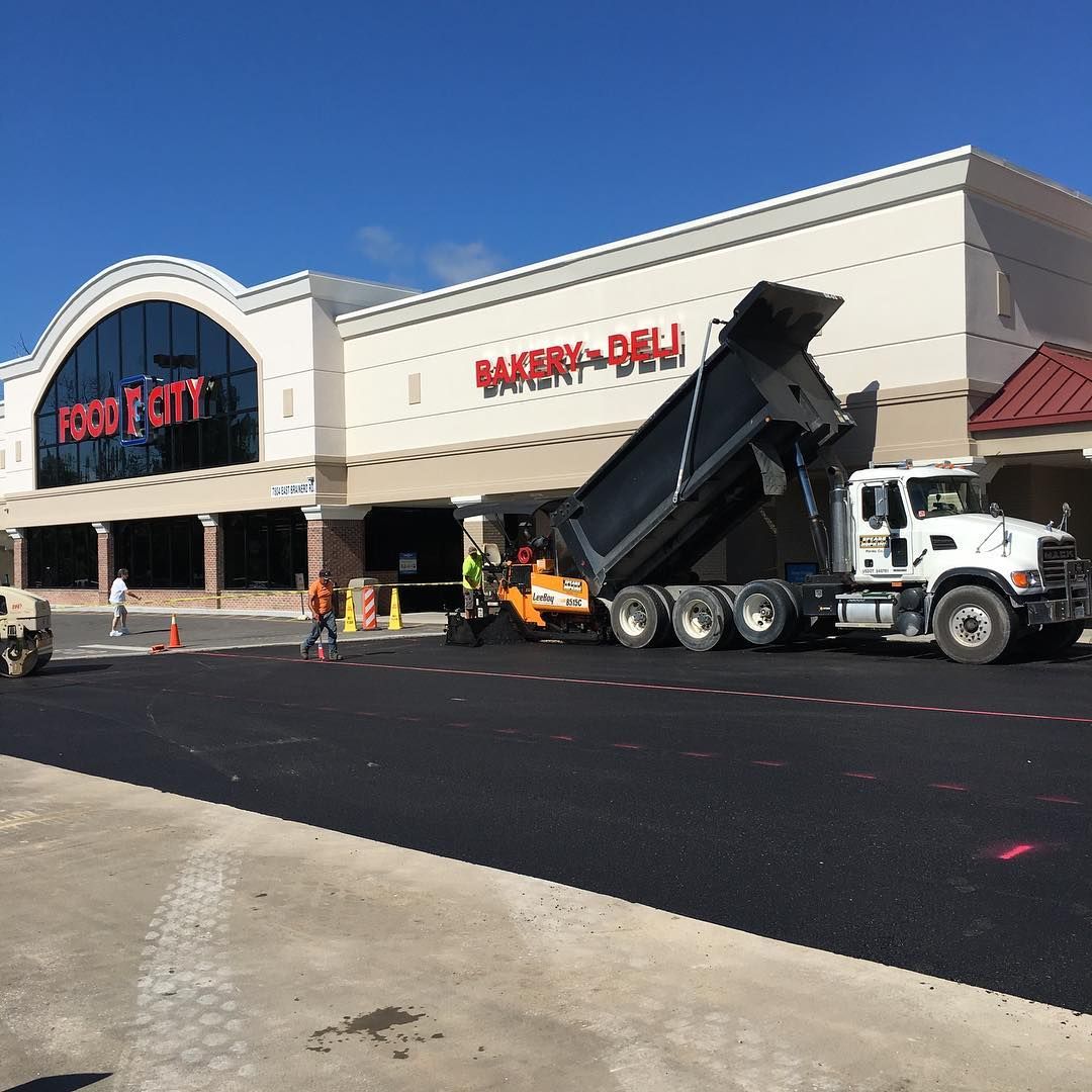 A dump truck is parked in front of a bakery deli