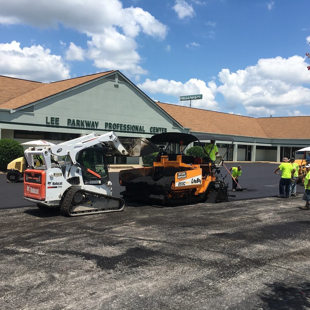A group of construction workers are working on a parking lot