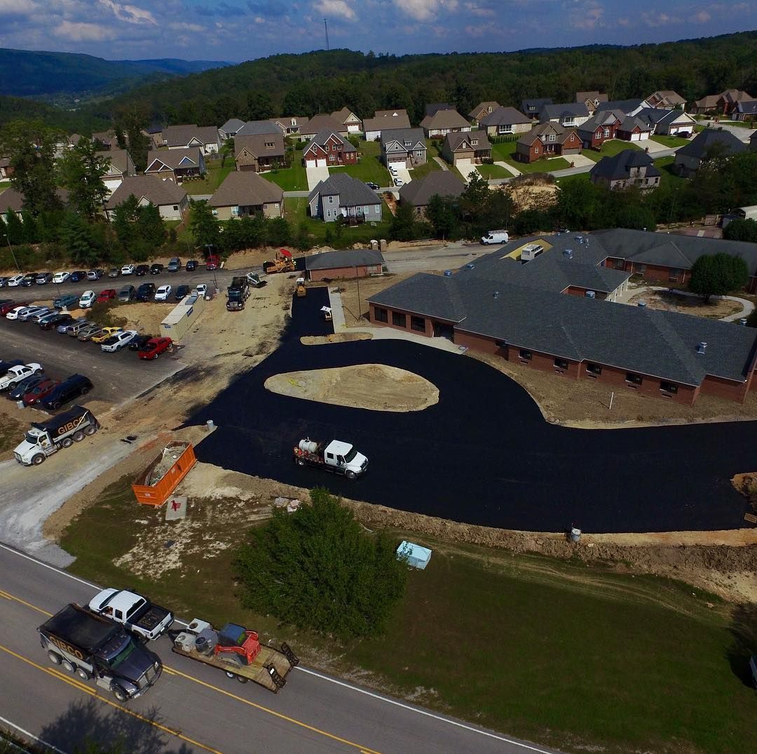 An aerial view of a construction site with a lot of cars parked on the side of the road