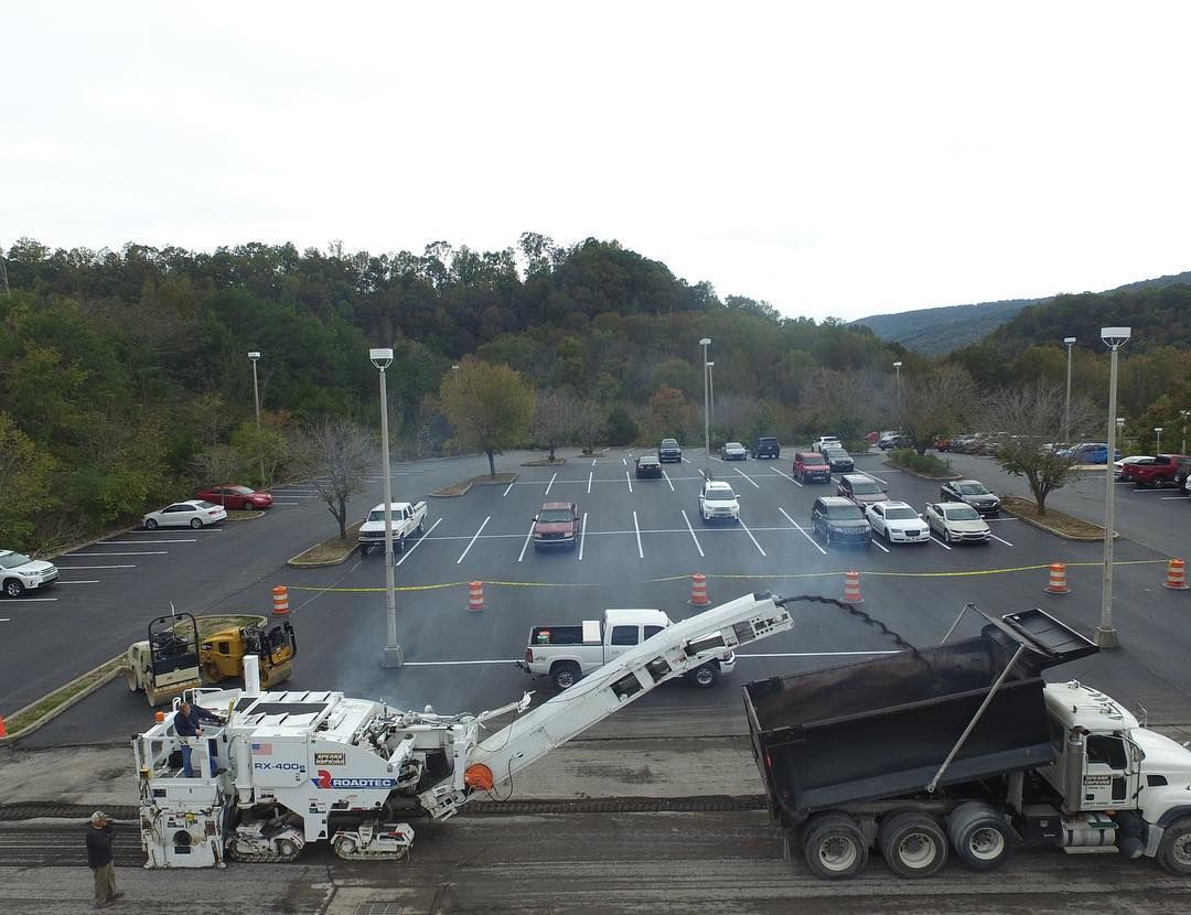 A dump truck is being loaded with asphalt in a parking lot.