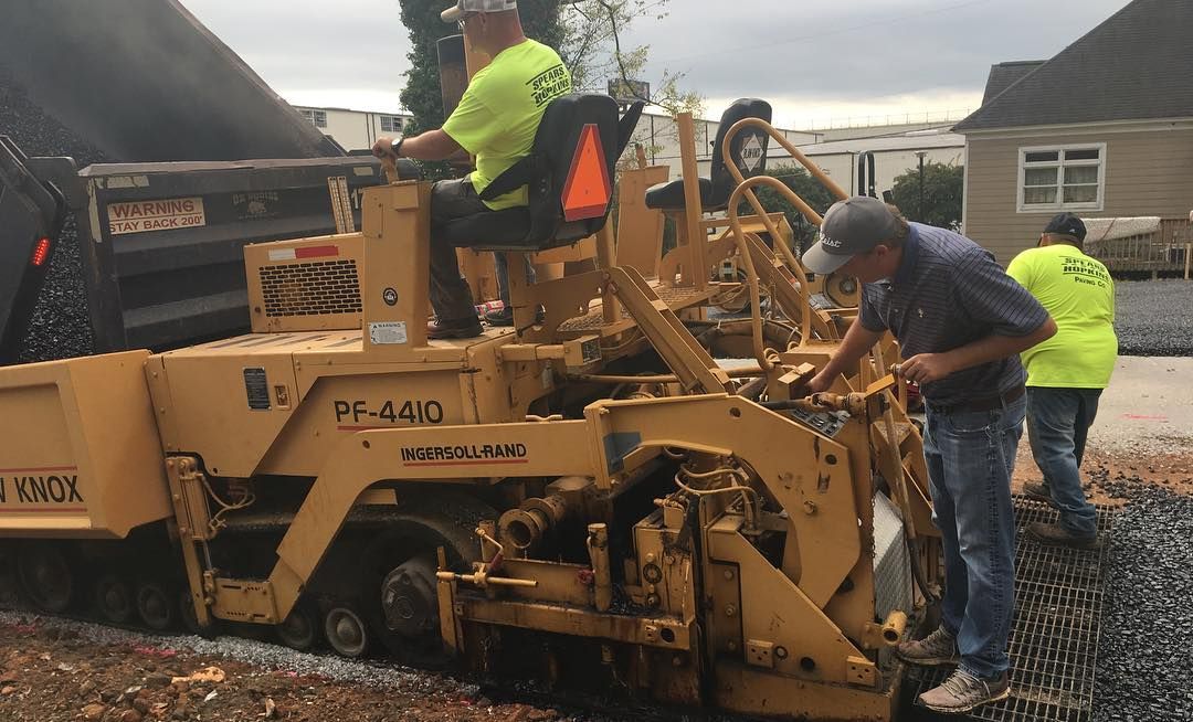 A group of men are working on a road with a machine.