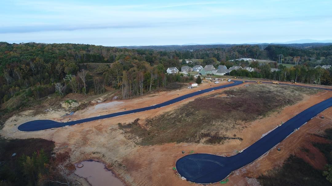 An aerial view of a road going through a lush green forest.