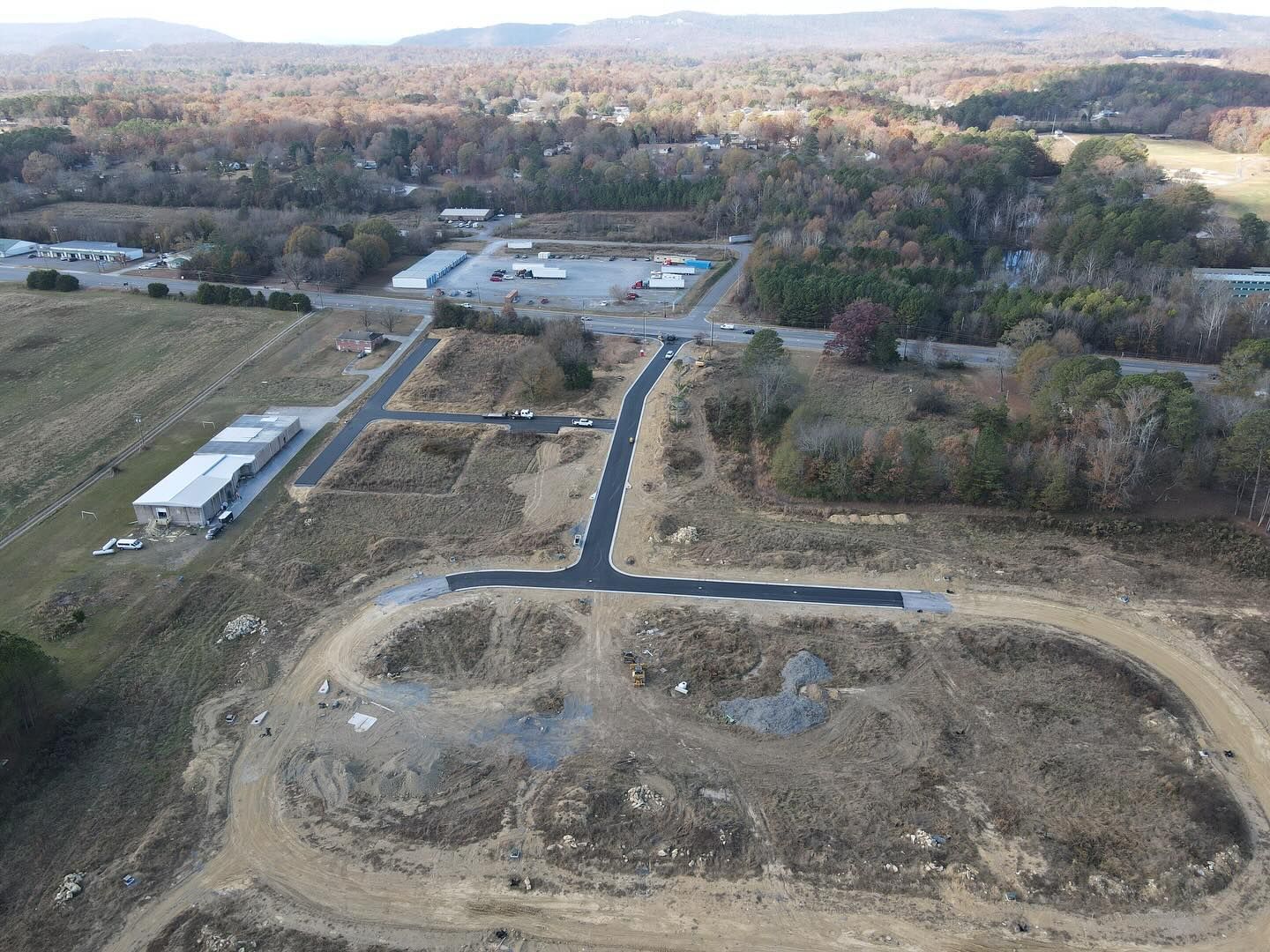 An aerial view of a construction site with a lot of dirt and trees in the background.