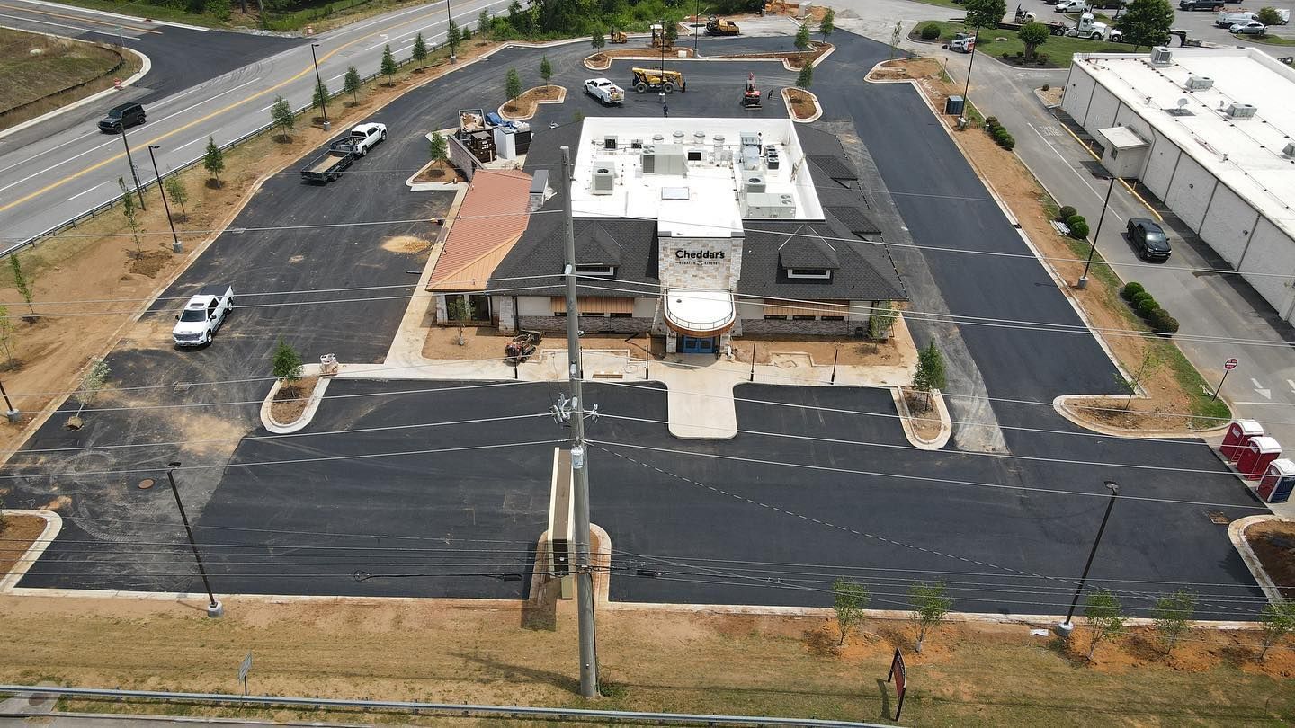 An aerial view of a parking lot with a building in the background.