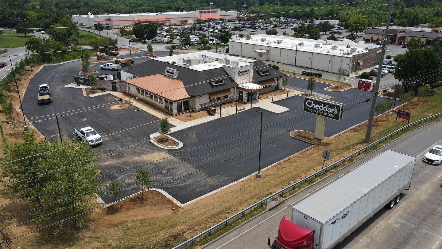 An aerial view of a truck driving down a highway next to a parking lot.
