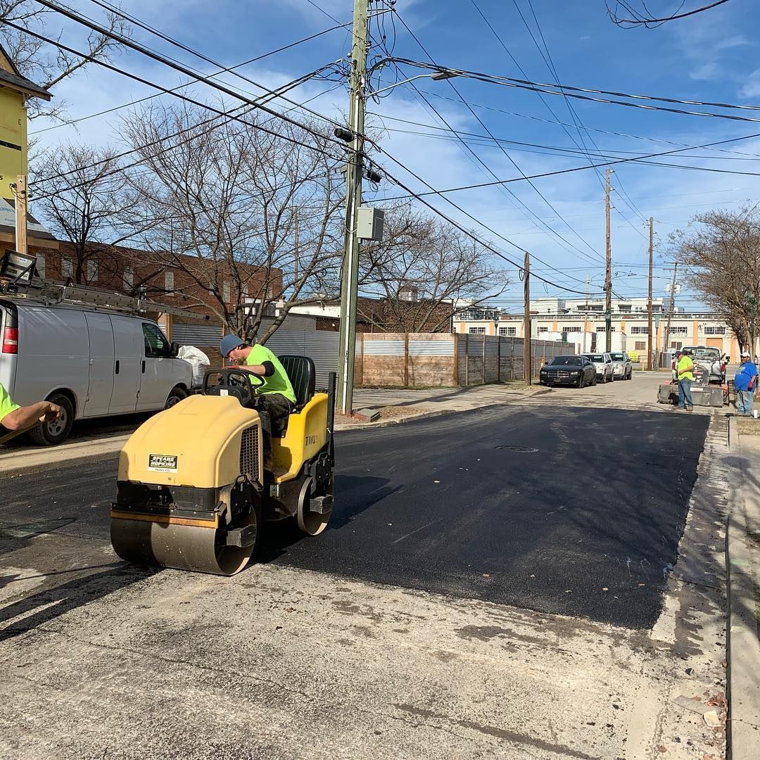 A man is driving a yellow roller on a street.