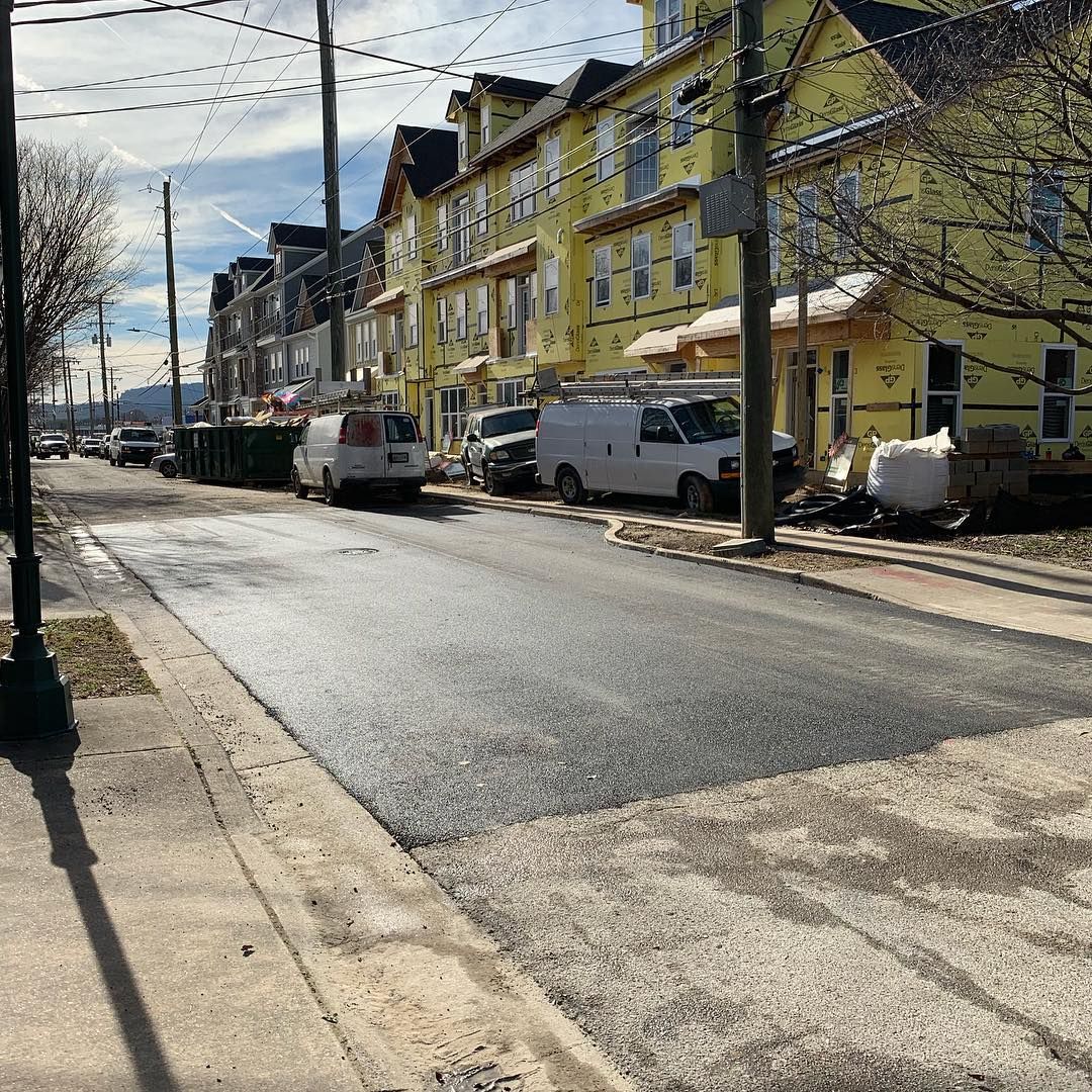 A white van is parked on the side of the road in front of a yellow building.