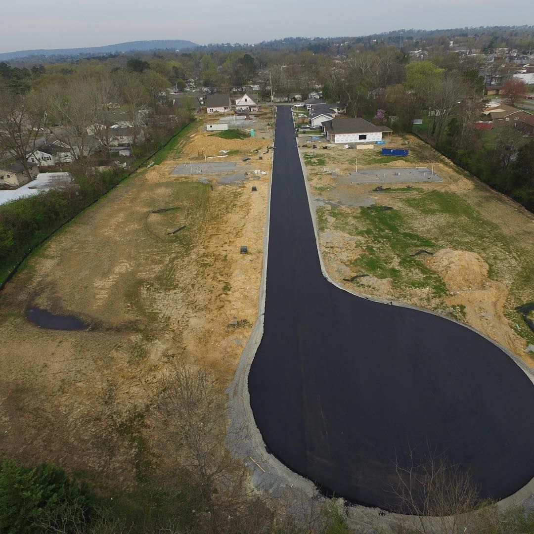 An aerial view of a road that is going through a field.