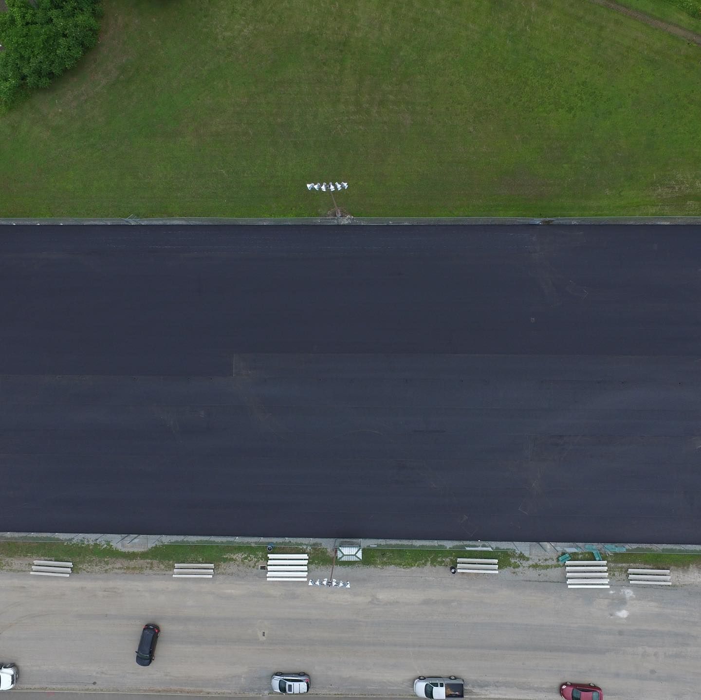 An aerial view of a parking lot with cars parked on the side of the road.