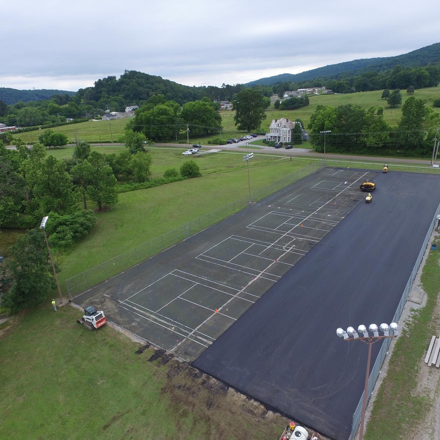 An aerial view of a tennis court being built in a field.