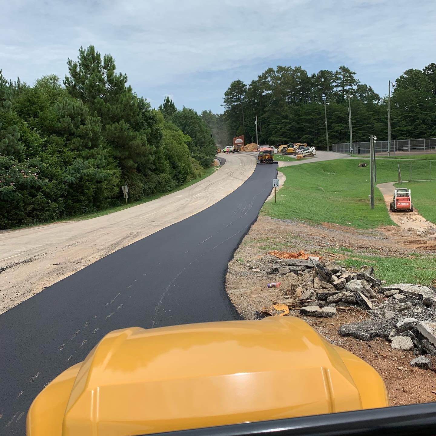 A yellow truck is driving down a dirt road