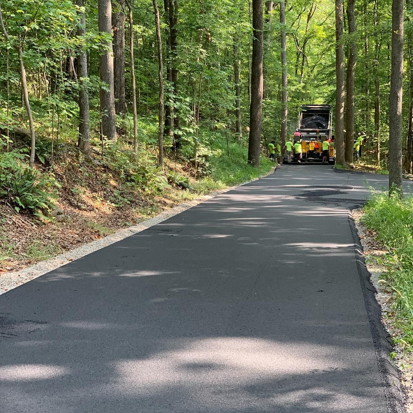 A truck is driving down a road in the woods.