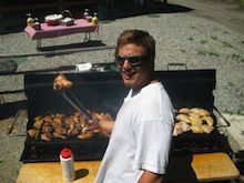 A man is standing in front of a grill cooking food.