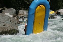 A blue and yellow raft is floating down a river.