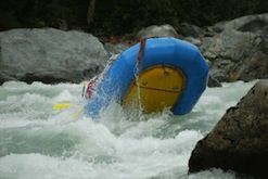 A blue and yellow raft is floating down a river.