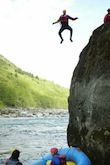 A man is jumping off a cliff into a river.