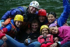 A group of people are posing for a picture on a raft in the water.