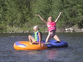 Two girls are floating on tubes in the water.