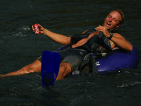 A man is floating on a tube in the water holding a coke can