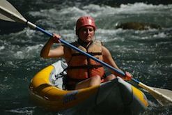 A woman is paddling a kayak down a river.