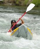 A man is paddling a kayak down a river.