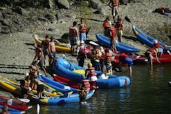 A group of people are standing on the shore of a lake.