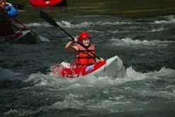 A man is paddling a kayak down a river.