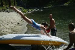 A woman is diving into a river on an inflatable raft.