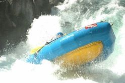 A blue and yellow raft is going through a waterfall.