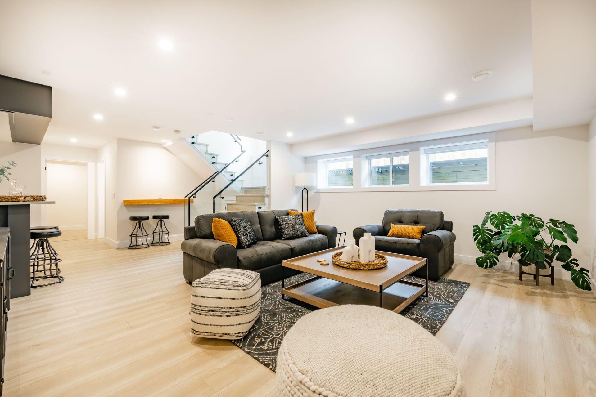 Spacious living room with gray sofas, wooden coffee table, and a stairwell in the background.