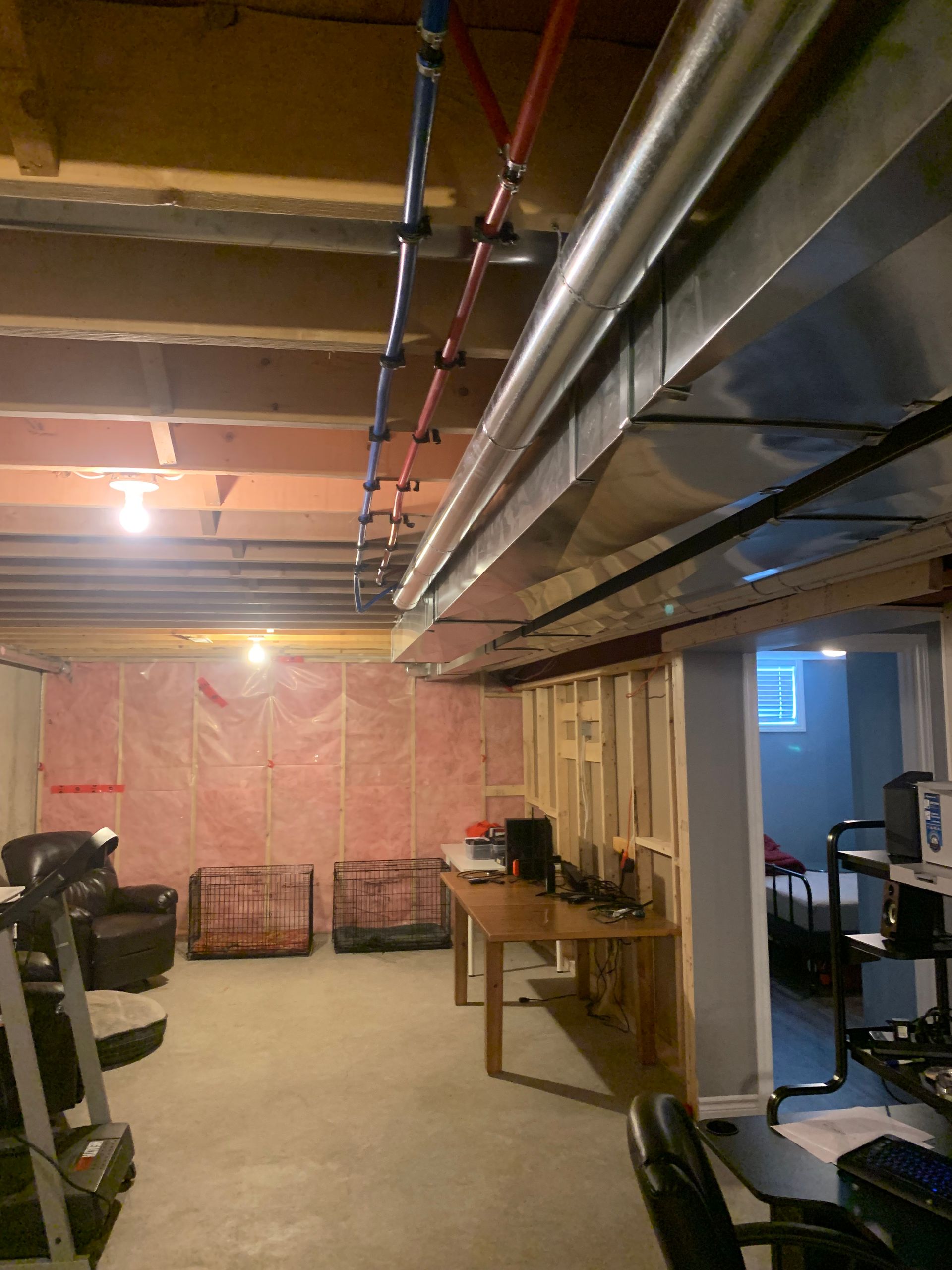 Basement interior with exposed pipes, ductwork, and insulation. Framed walls, and concrete floor.