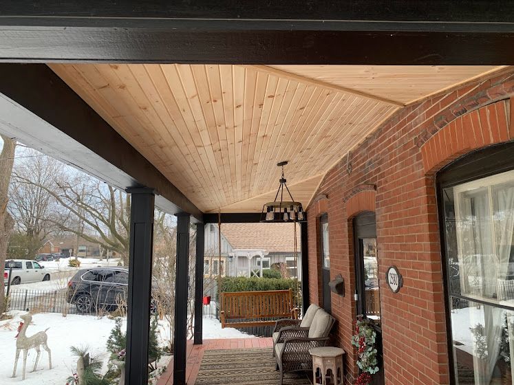 A porch with a wooden ceiling and a swing.