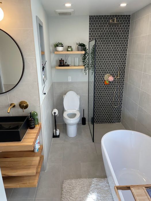 Modern bathroom with a black sink, floating shelves, and a gray-tiled shower.