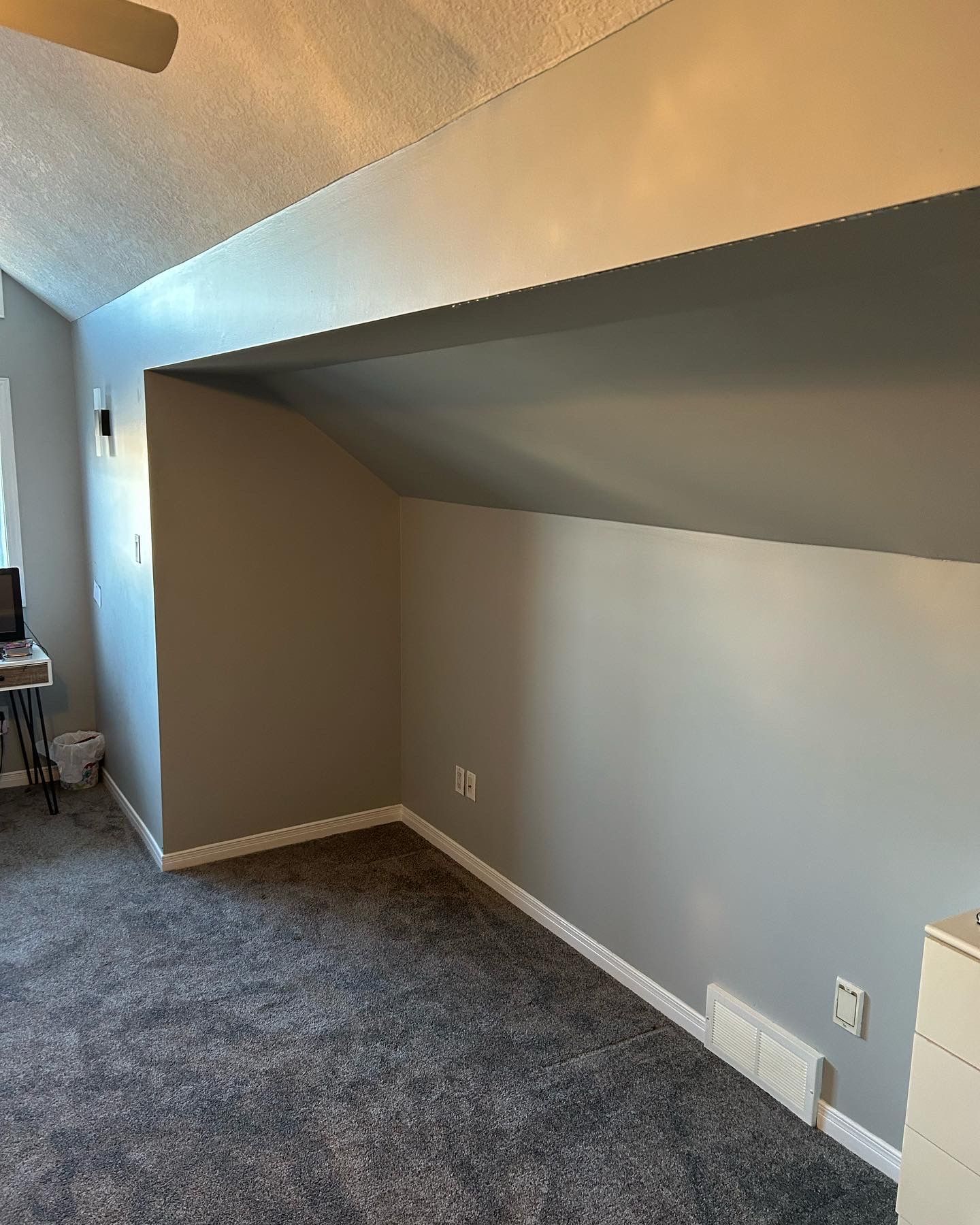 Gray-painted room with angled walls, white trim, and dark gray carpet.