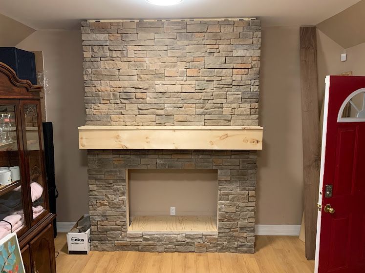 Stone fireplace with a wooden mantle and an empty firebox.