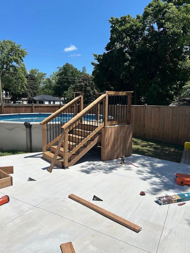 Wooden deck and stairs leading to an above-ground pool, on a concrete patio.