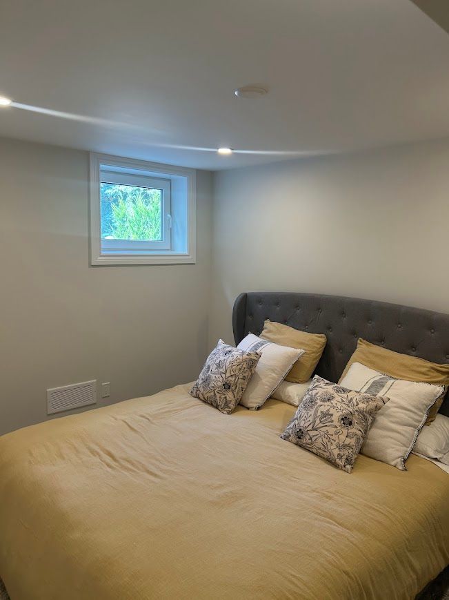 Bedroom with bed, pillows, window, and neutral walls.