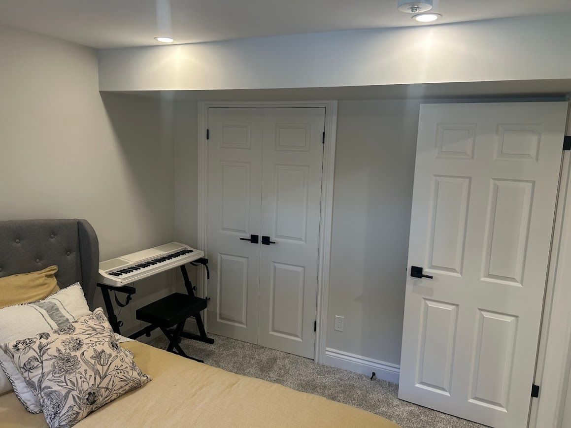 Bedroom with a bed, piano, and two white doors.